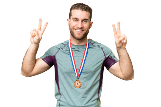Young handsome blonde man with medals over isolated chroma key background showing victory sign with both hands