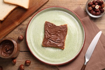 Toast with tasty nut butter and hazelnuts on wooden table, flat lay