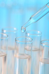 Laboratory analysis. Dripping liquid from pipette into glass test tube on light blue background, closeup