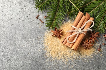 Different spices and fir branches on gray table, flat lay. Space for text