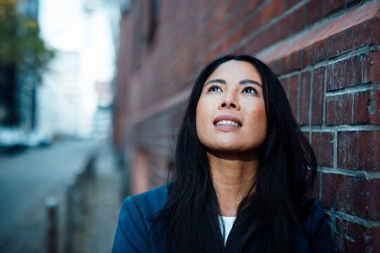 Contemplative businesswoman near brick wall