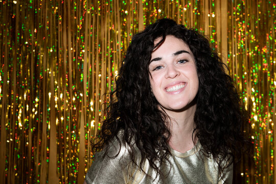 Happy young woman in front of tinsel curtain