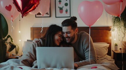 Happy loving couple shopping online while lying in bed and using laptop with heart shape balloons - obrazy, fototapety, plakaty