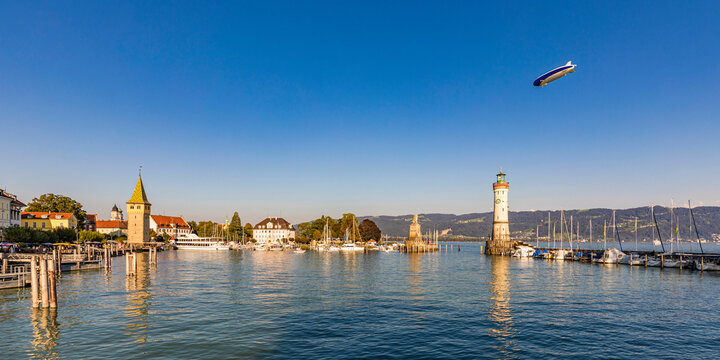 Germany, Bavaria, Lindau, Marina of town on shore of lake Bodensee with blimp flying in background