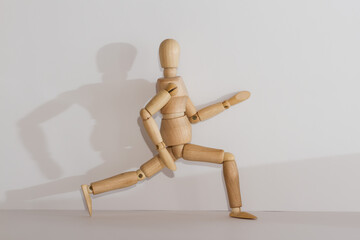A wooden mannequin imitates a step, a lunge on a light background.