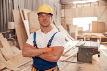 Joyful male worker standing in carpentry workshop
