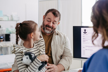 Doctor explaining test results to father of young girl patient. Concept of children healthcare and emotional support for child patients.