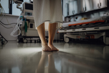 Close up of barefoot legs of patient, standing by hospital bed in emergency room. Anxiety, worry...