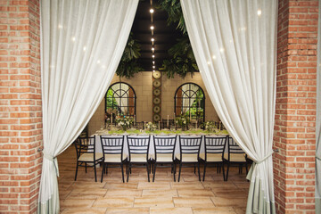 Set table at a wedding banquet in the park. Patio with a cozy romantic little restaurant . Summer veranda with white curtains 