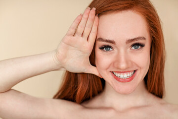 Fototapeta premium Redhead woman touching face and smiling