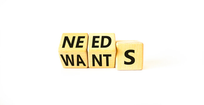 Wants or needs symbol. Turned wooden cubes and changed the word wants to needs. Beautiful white table, white background, copy space. Business and wants or needs want need concept.