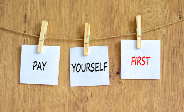 Pay yourself first symbol. Concept words Pay yourself first on beautiful white paper on clothespin. Beautiful wooden table wooden background. Business and pay yourself first concept. Copy space.