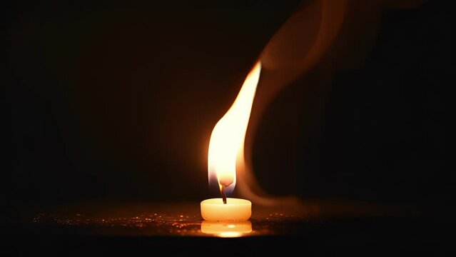 Footage of a candle burning until the very end, with the last remaining smoke from the wick fading away into the darkness.