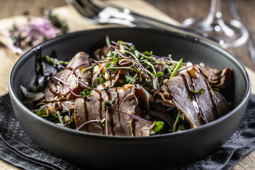Roast beef salad with herbs and balsamic sauce in the style of a bowl on a restaurant table - Close...