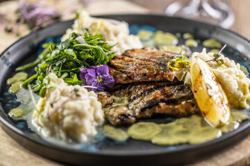 Grilled trout fillet with mashed potatoes and lemon sauce on a restaurant plate