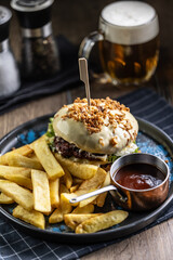 Beef burger topped with cheese with fries and draft beer on a pub or restaurant plate