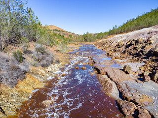 Aerial drone view of Tinto river in Huelva mountains. Red coloration has its origin in the weathering of minerals containing heavy metal sulfides found in deposits along the river and at its source
