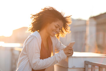 Outdoor portrait of happy cheerful african american woman in headphones using smartphone