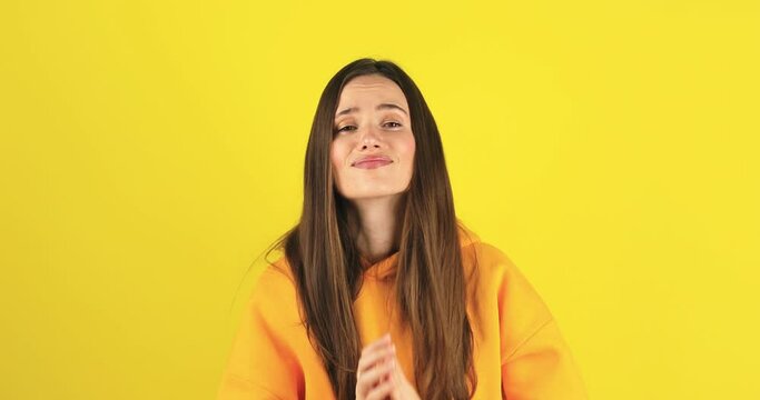 Sad attractive brunette caucasian stylish girl brunette hair in casual yellow hoody, showing, pointing two thumbs at herself, please choose me, hand in pray gesture isolated on yellow background.