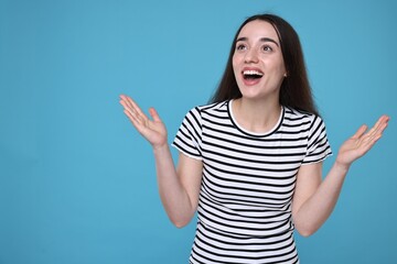 Portrait of happy surprised woman on light blue background. Space for text