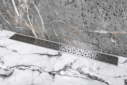 Stainless linear shower drain system in shower room.