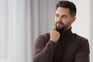 Fototapeta na wymiar Handsome man in stylish sweater indoors, space for text