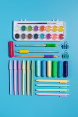 Stylish stationery on a blue background. Back to school. Paints, markers and colorful pens.