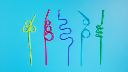 Colorful plastic cocktail straws on a blue background. Flat lay
