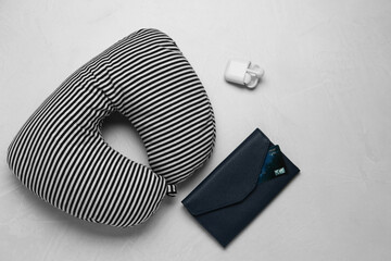 Striped travel pillow, wallet with credit card and earphones on gray background, flat lay