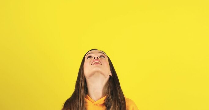Look at advertisement! Teen stylish girl pointing up, saying to subscribe, showing place for commercial, promotional information below. Young woman isolated yellow background. Look at up.