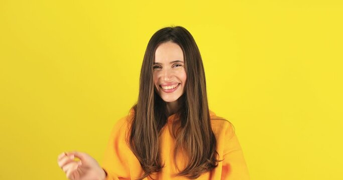 Brunette woman on a yellow background with a gesture showing that she liked the treat. Belisimo. Girl pout lips show belissimo perfect sign, gesture of a good taste.