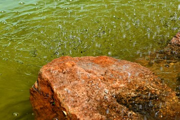 superbe rocher orange au dessous d'une petite chute d'eau formant une cascade avec son eau verte et...