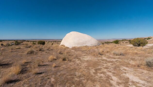 a quiet landscape a strong vanishing point a big white rock in a dry landscape under a blue sky