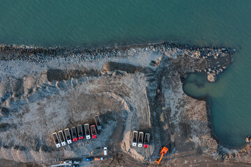 Aerial view of excavator and dump trucks in construction site by the sea side. Construction industry