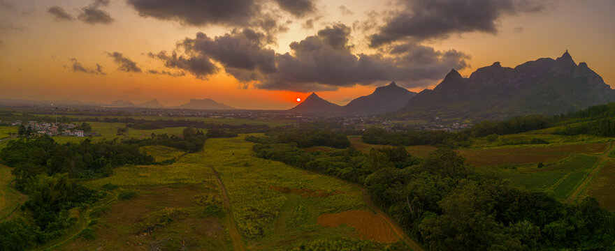 View of golden sunset behind Long Mountain and patchwork of green fields, Mauritius