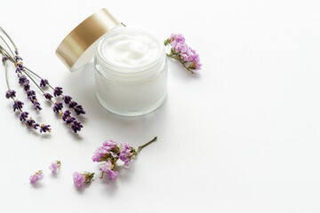 Obraz na płótnie Canvas Glass vial of cosmetic face skin care cream with flowers