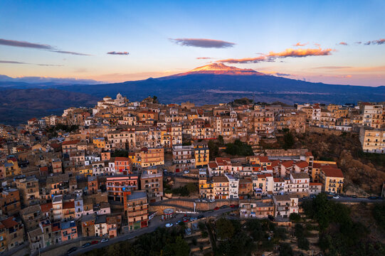 Aerial view of the old village of Centuripe with Mount Etna volcano covered with snow and lit by the sunset, Centuripe, Enna province, Sicily, Mediterranean