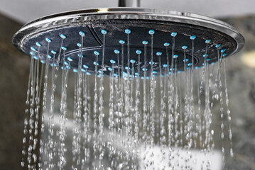 Water flowing from circle shower head in modern bathroom.