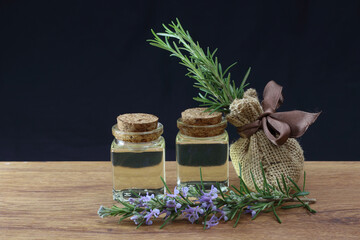 Rosemary essential oil in glass bottle on dark background