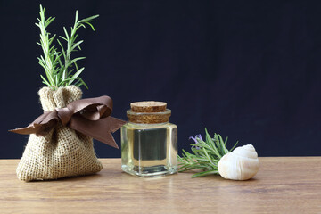 Rosemary essential oil in glass bottle and snail shell on dark background