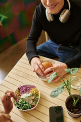 overhead view of young diverse couple enjoying vegan meal in cafe, burger with tofu and salad bowl
