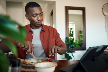 African man watching something on a digital tablet over breakfast