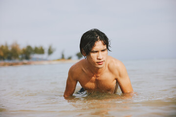 Active Man Enjoying Summer Vacation: Smiling Asian Athlete Having Fun Swimming in a Tropical Ocean