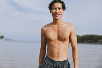 Active Man Enjoying Tropical Summer Vacation: Smiling Asian Male Swimming in Blue Ocean, Creating a Splash of Joy and Freedom