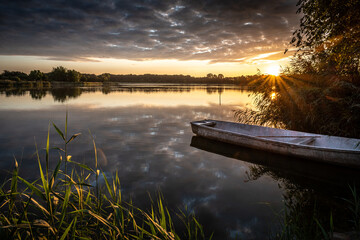 cudowny wschód słońca nad jeziorem i łódka przy brzegu - obrazy, fototapety, plakaty