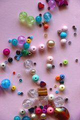 Various colorful beads on bright pink background. Top view.