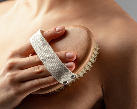Woman rubbing her body with a dry massage brush
