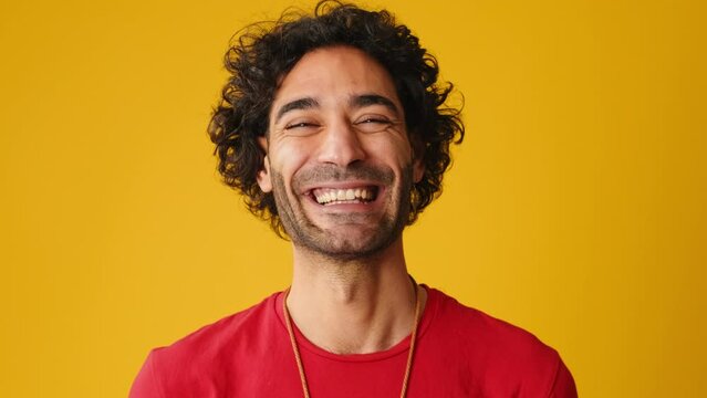 Close up, laughing man looks at camera isolated on yellow background in studio