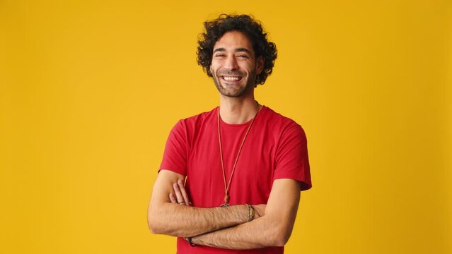 Happy man crossing his arms and looking at camera isolated on yellow background in studio