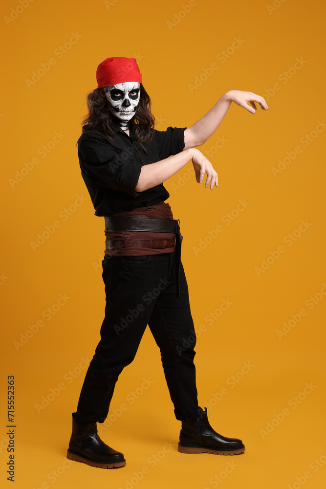 Sticker Man in scary pirate costume with skull makeup posing on orange background. Halloween celebration